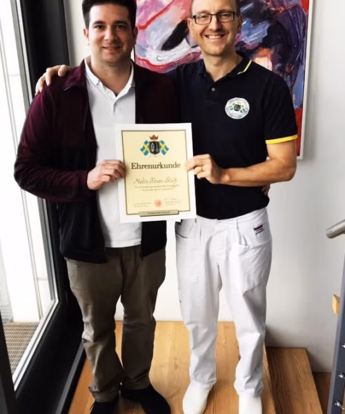 Chiropraktiker Metin Kenan Sisik aus Ulm präsentiert seine Ehrenurkunde als Master of Chiropractic nach dem Dr. Ackermann Konzept.