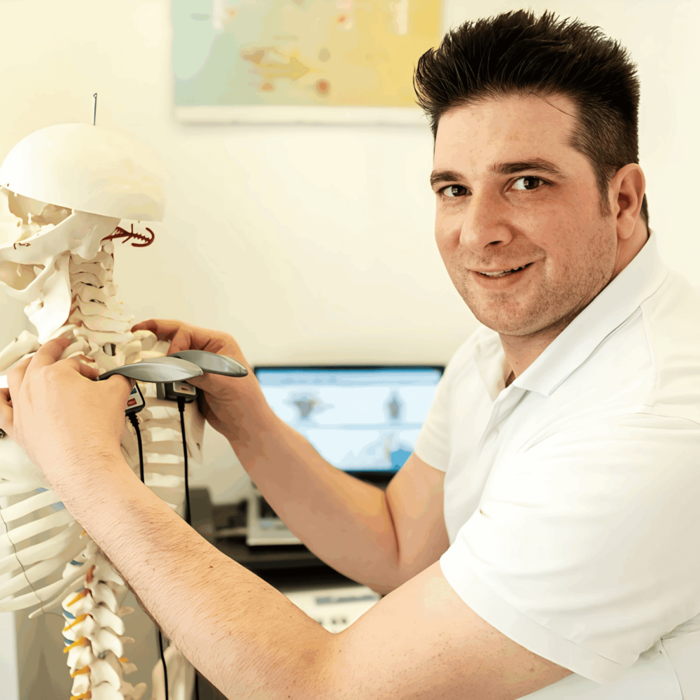 Chiropraktiker Metin Kenan Sisik demonstriert in seiner Praxis in Ulm chiropraktische Zusammenhänge an einem Skelettmodell zur Patientenaufklärung.